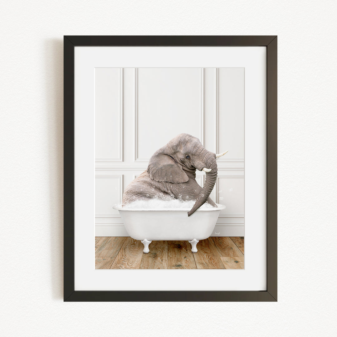 A gray elephant is sitting in a white bathtub, with its trunk raised and appearing to be enjoying the bath.