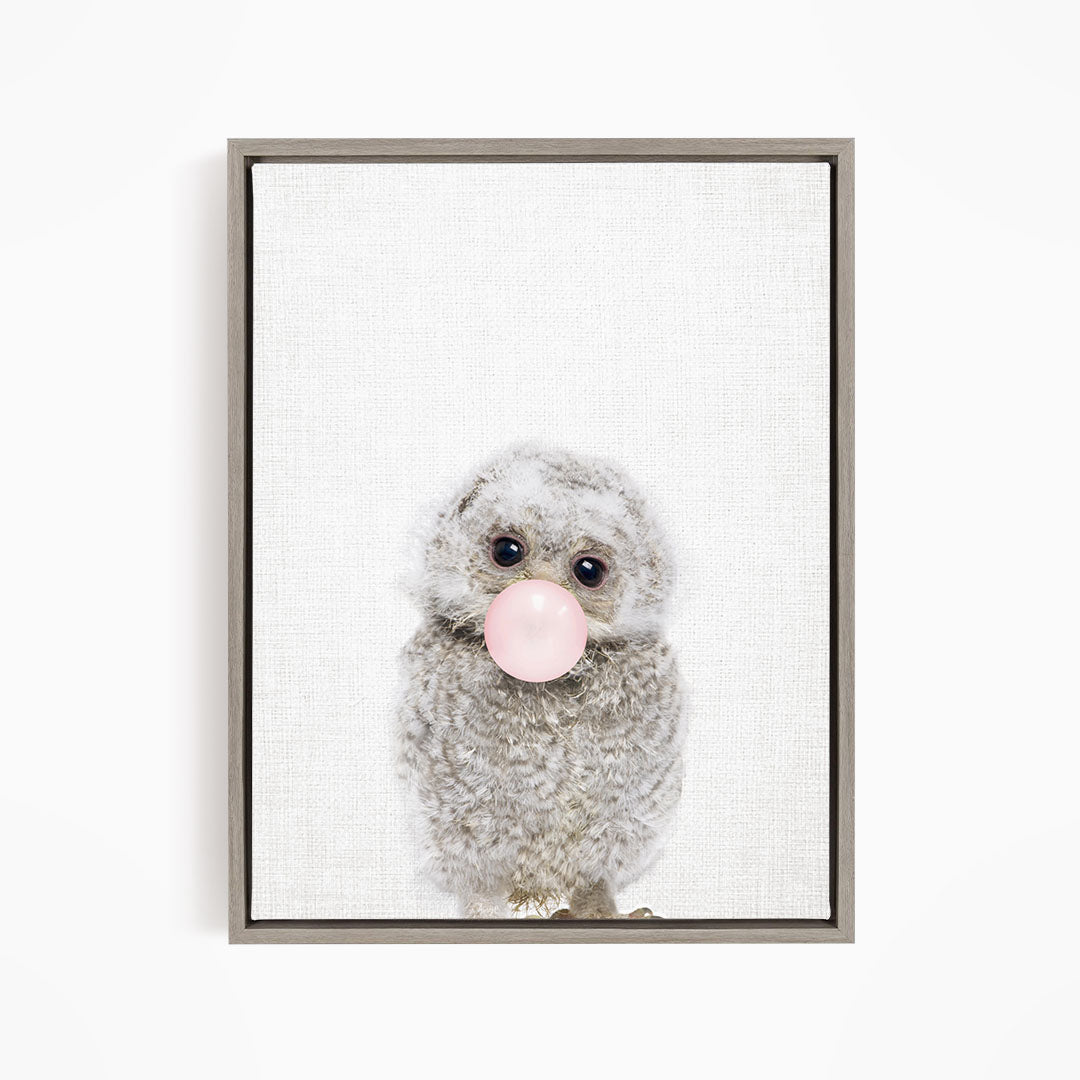 A cute gray owl with large eyes is blowing a bubble with a pink bubble gum bubble.