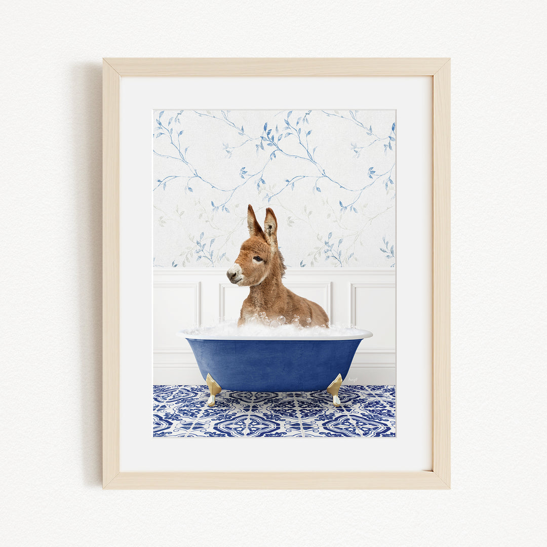 A donkey is sitting in a blue bathtub filled with bubbles, surrounded by a blue and white patterned rug and a white wall with blue floral wallpaper.