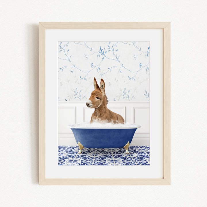 A donkey is sitting in a blue bathtub filled with bubbles, surrounded by a blue and white patterned rug and a white wall with blue floral wallpaper.