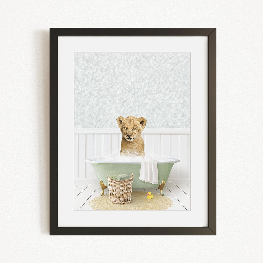 A young lion cub sitting in a green bathtub filled with water, surrounded by a basket of toys and a yellow rubber duck.