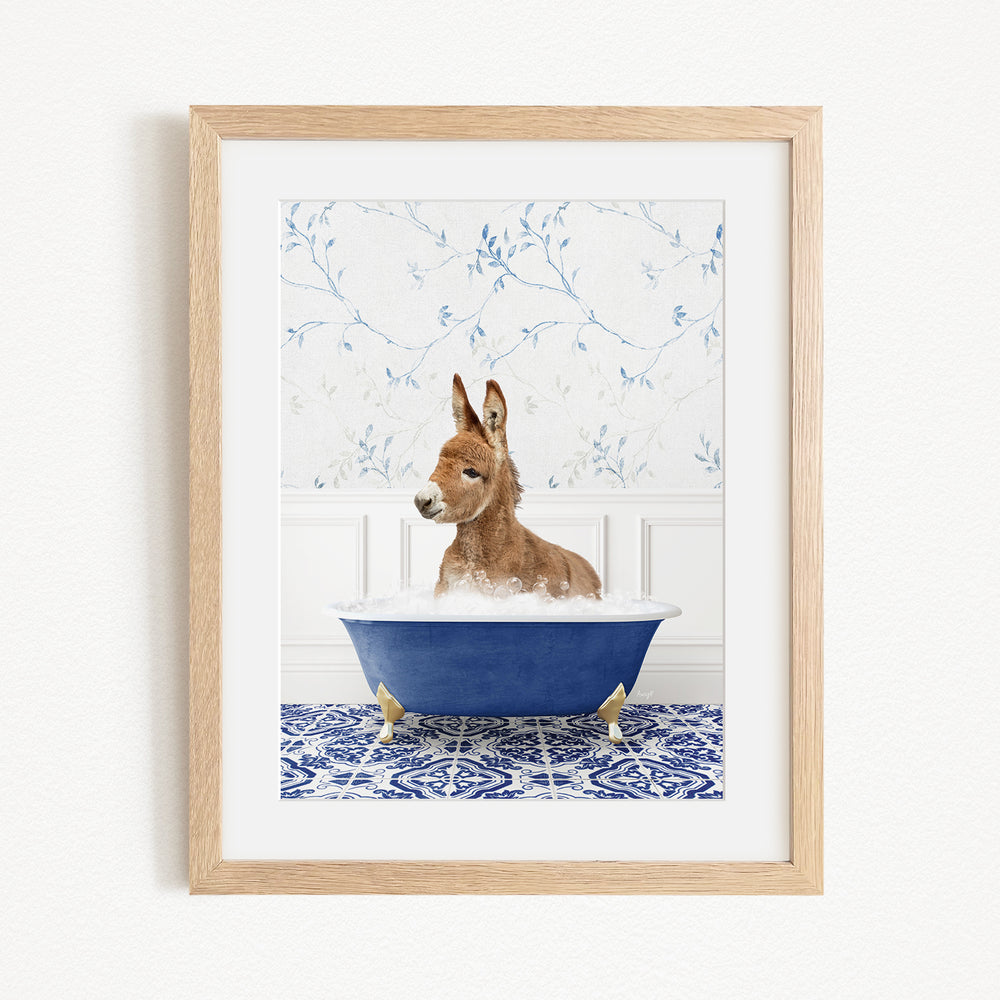 A donkey is sitting in a blue bathtub filled with water, surrounded by a patterned tile floor and a floral wallpaper background.