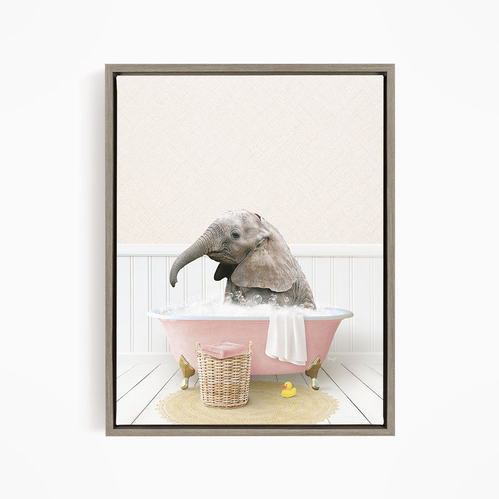 A gray elephant is sitting in a pink bathtub filled with water, surrounded by a yellow rubber duck and a basket of bath toys.