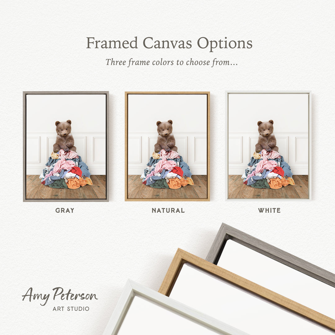 three framed canvas options, each featuring a teddy bear sitting on a pile of clothes. The options include a gray frame, a natural frame, and a white frame.