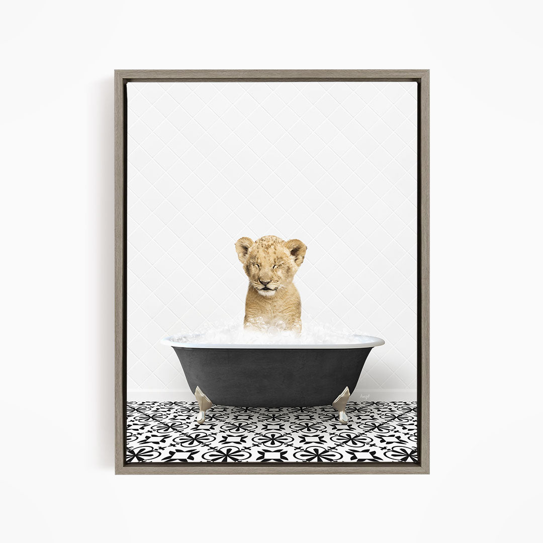 A young lion cub sitting in a bathtub filled with water, looking up at the camera.