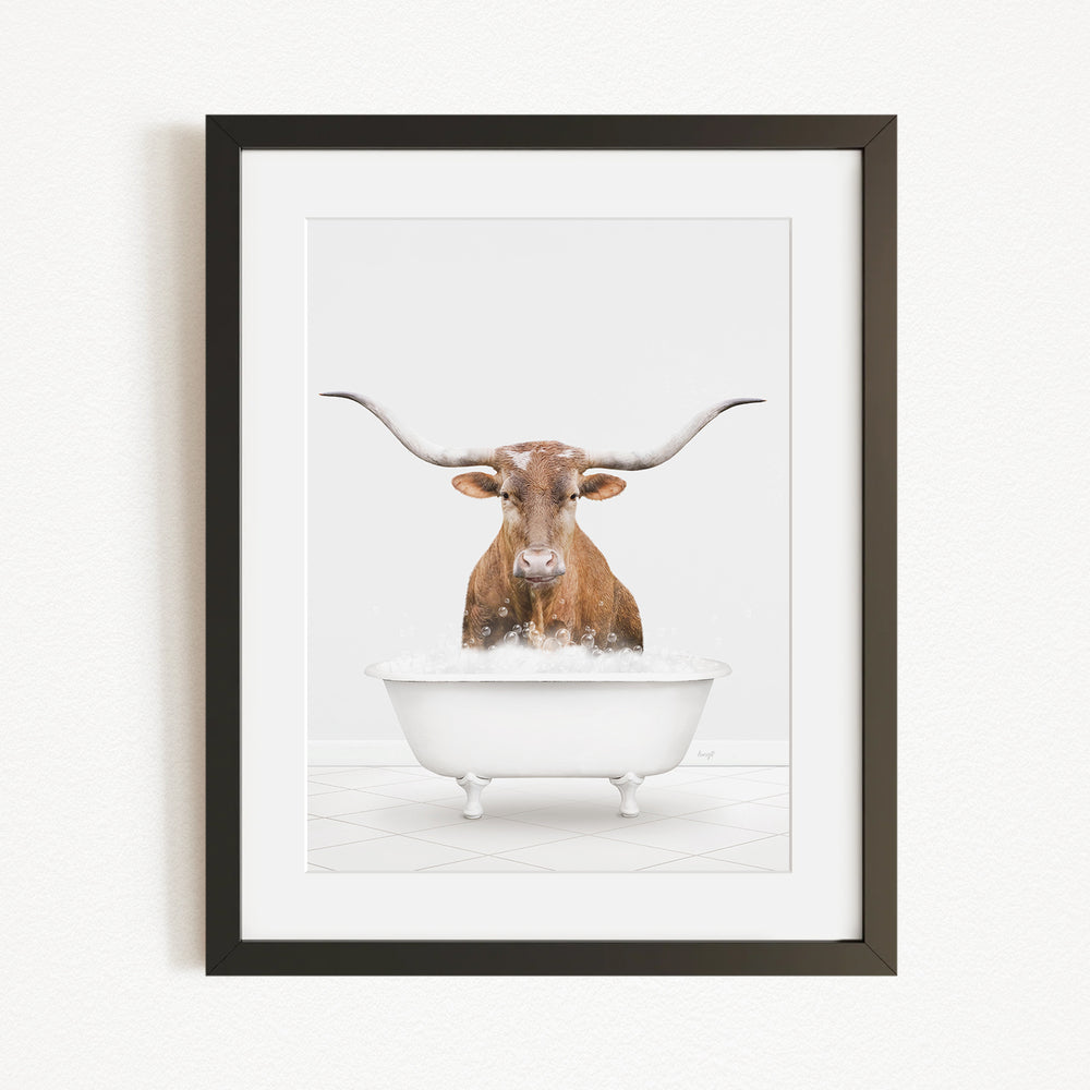 A brown cow with long horns is sitting in a white bathtub filled with water, appearing to be enjoying a bath.