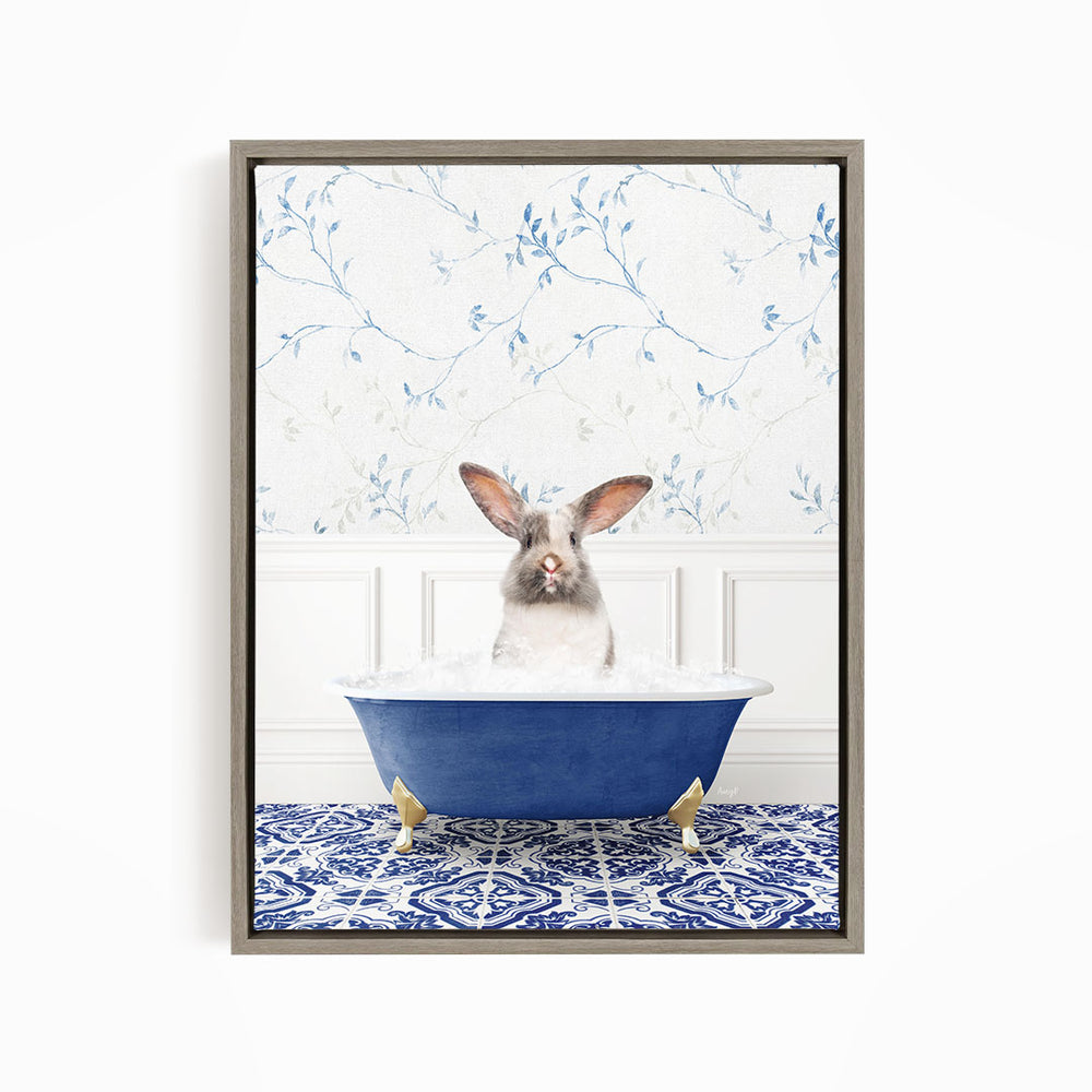 A white rabbit with brown ears is sitting in a blue bathtub filled with water, surrounded by a blue and white patterned rug on the floor.