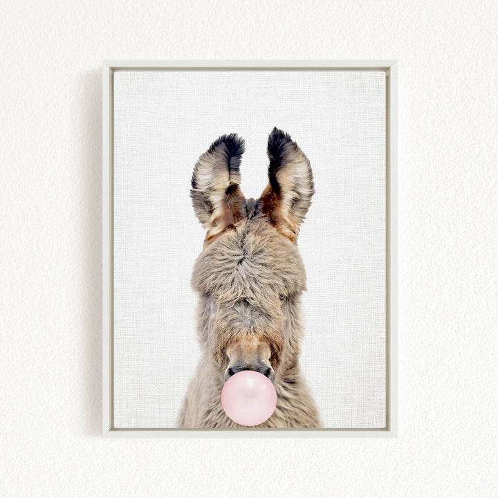 A donkey with its head tilted upwards and a pink bubble gum bubble in its mouth.