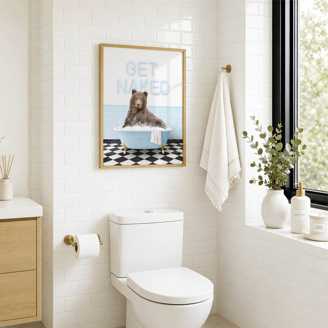 A bathroom with a white toilet, a framed poster of a bear sitting in a bathtub, and a window with greenery outside.