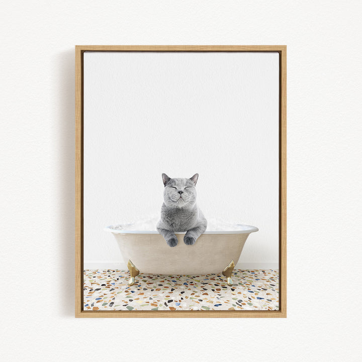 A gray cat sitting in a white bathtub filled with bubbles, with a speckled floor in the background.