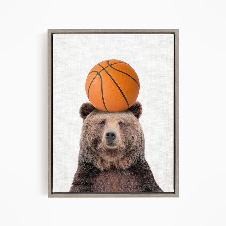 A brown bear balancing a basketball on its head.