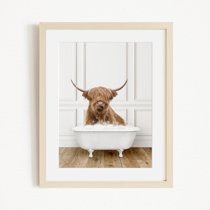 A brown cow with long horns is sitting in a white bathtub filled with bubbles, creating a whimsical and playful scene.