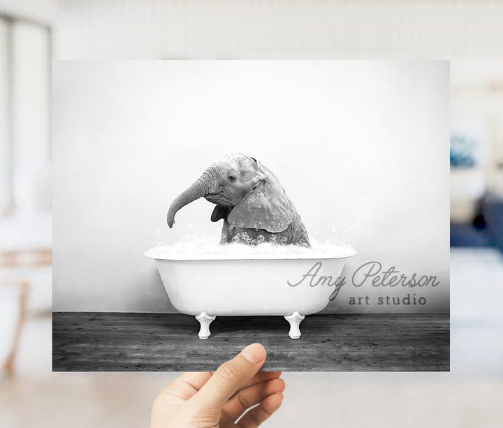 a person holding up a picture of an elephant in a bathtub