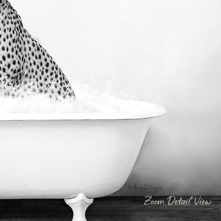 A close-up black and white image of a bathtub filled with water and bubbles, with a spotted animal's leg partially submerged in the water.