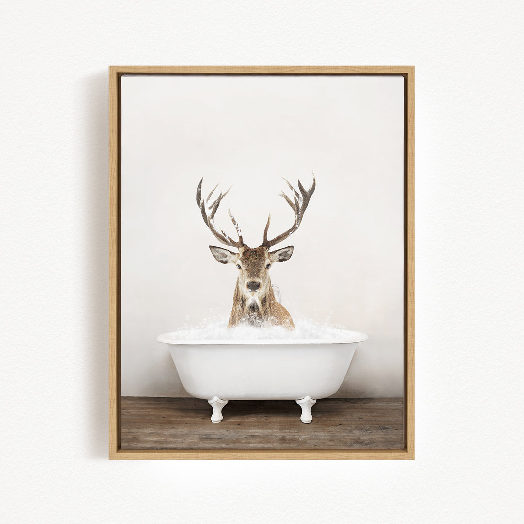 A deer with large antlers is sitting in a white bathtub filled with water, creating a whimsical and unexpected scene.