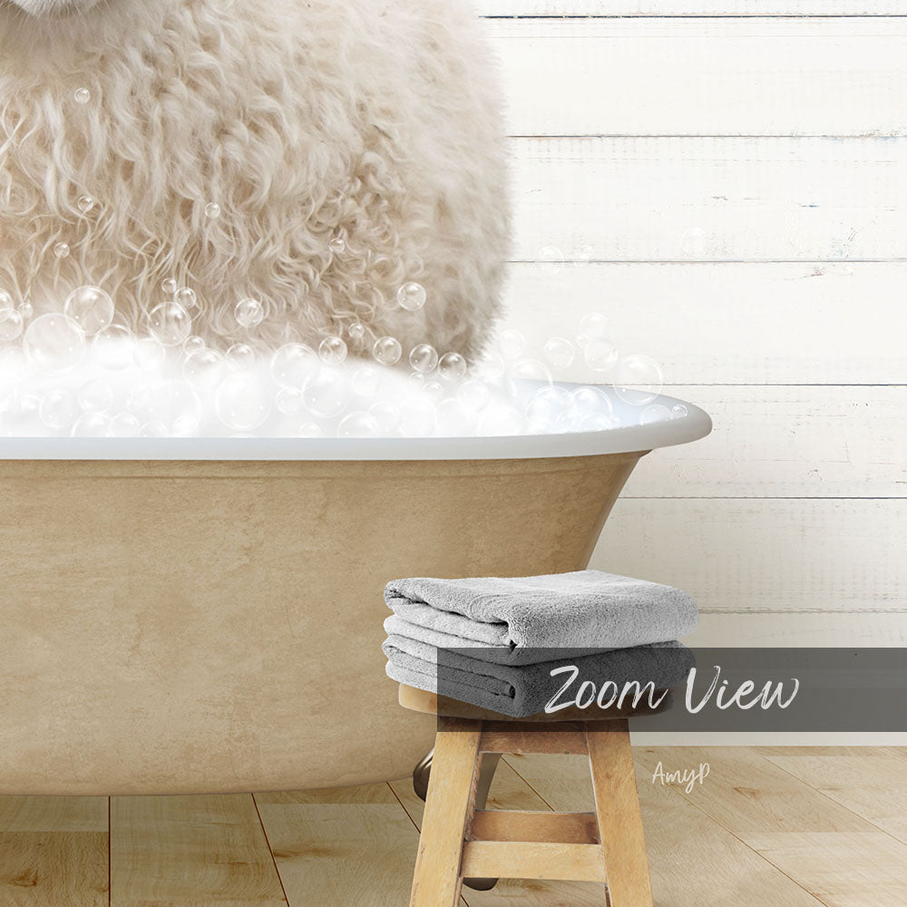A fluffy white dog is sitting in a bathtub filled with bubbles, with a towel and stool nearby.