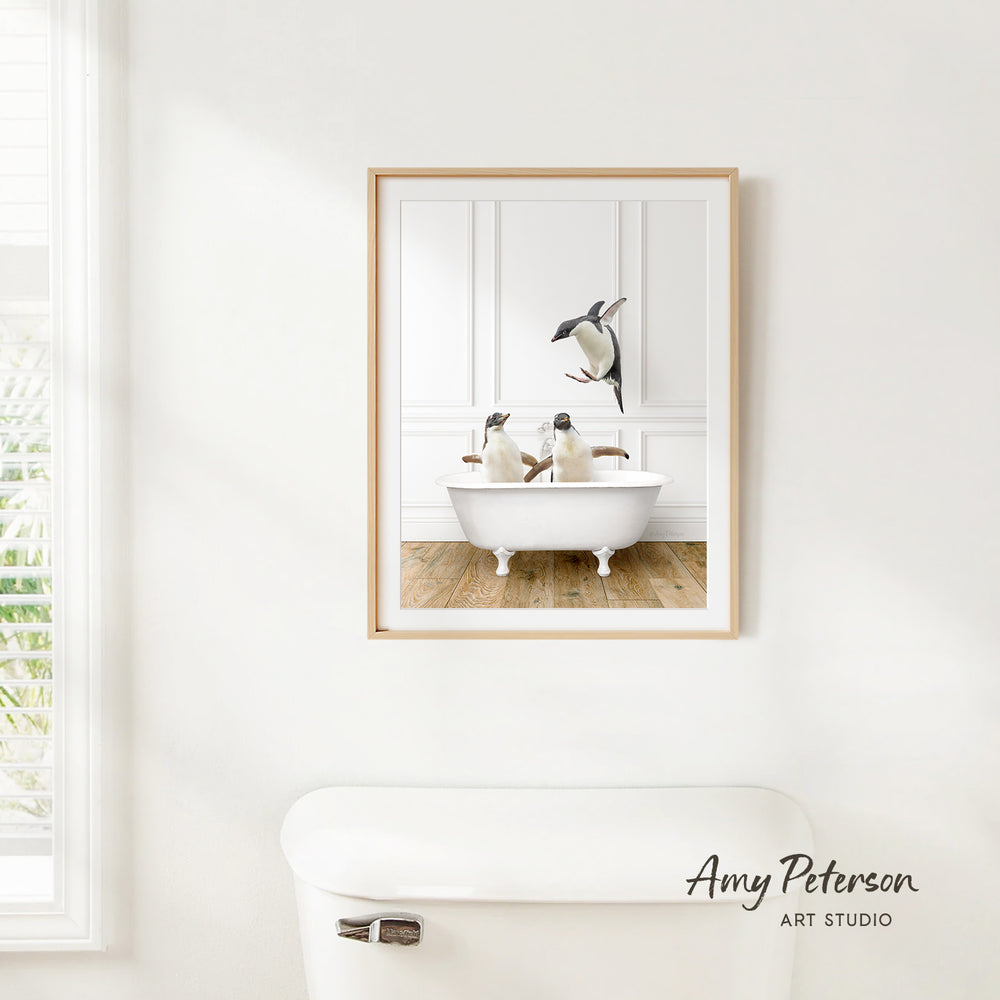A framed image of two penguins sitting in a bathtub, with one penguin standing on the edge of the tub.