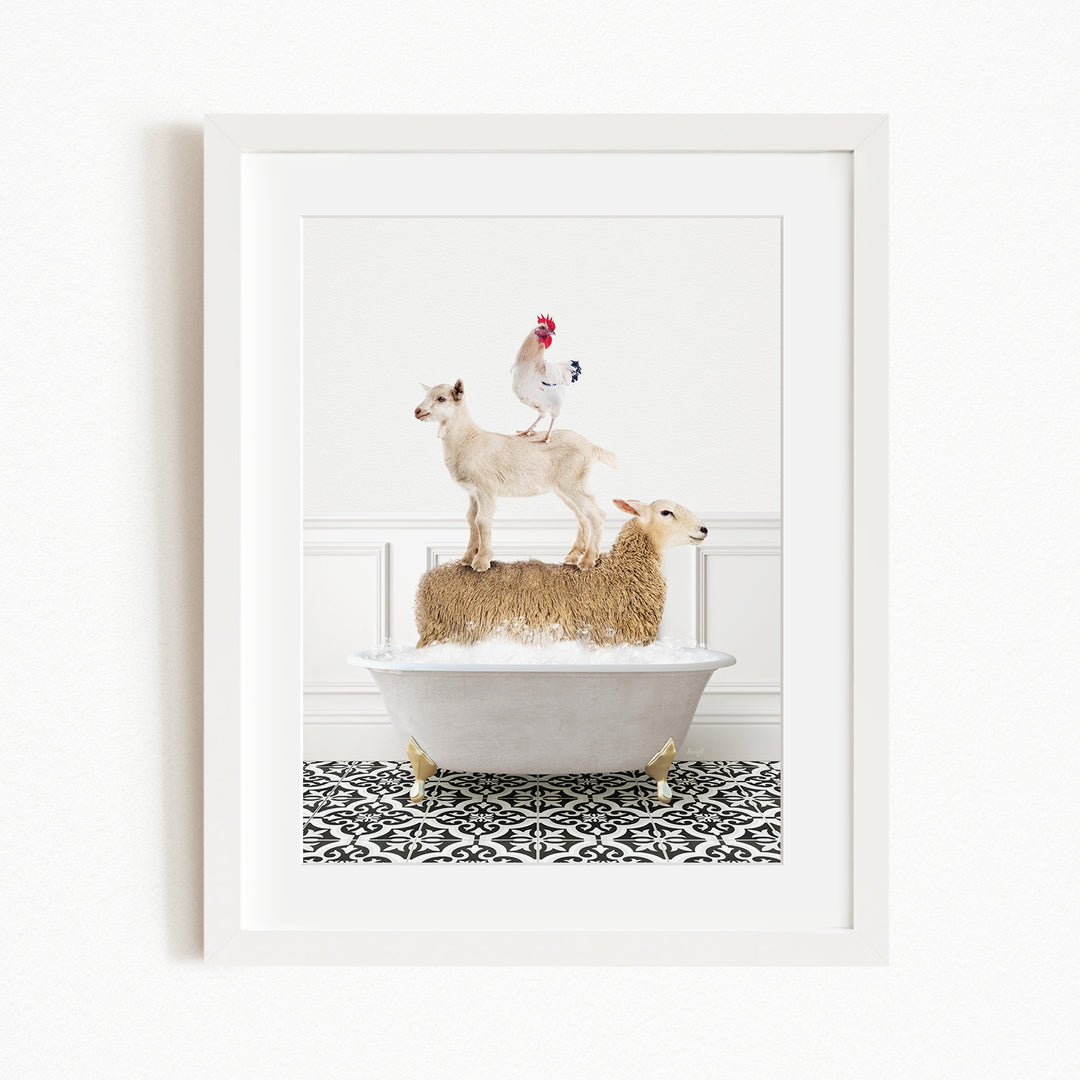 A framed image depicting a goat standing on a sheep's back while a rooster stands on top of the sheep, all in a white bathtub.