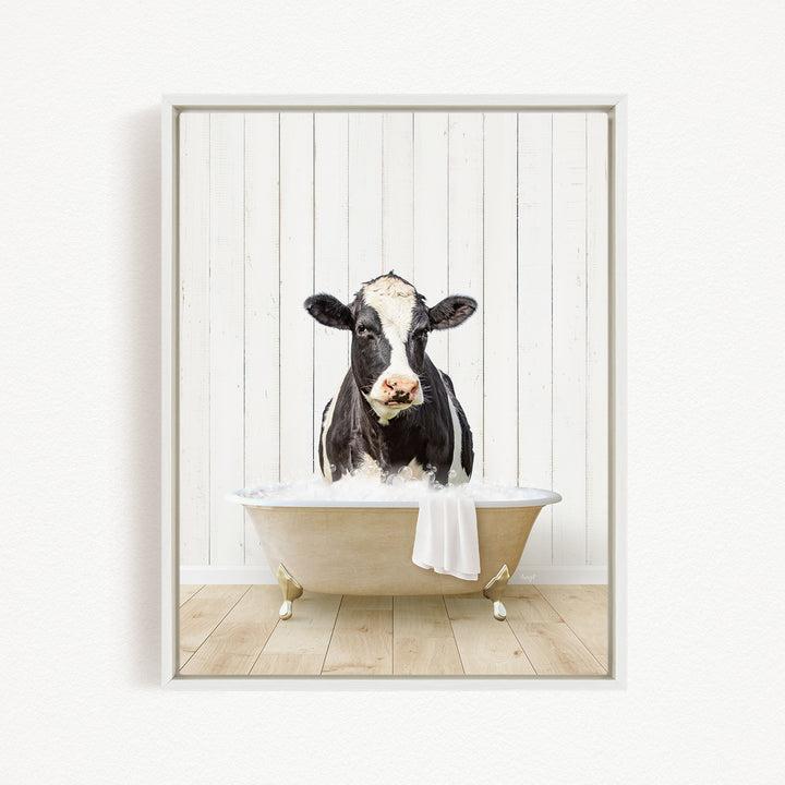 A black and white cow is sitting in a bathtub filled with water, creating a whimsical and humorous scene.