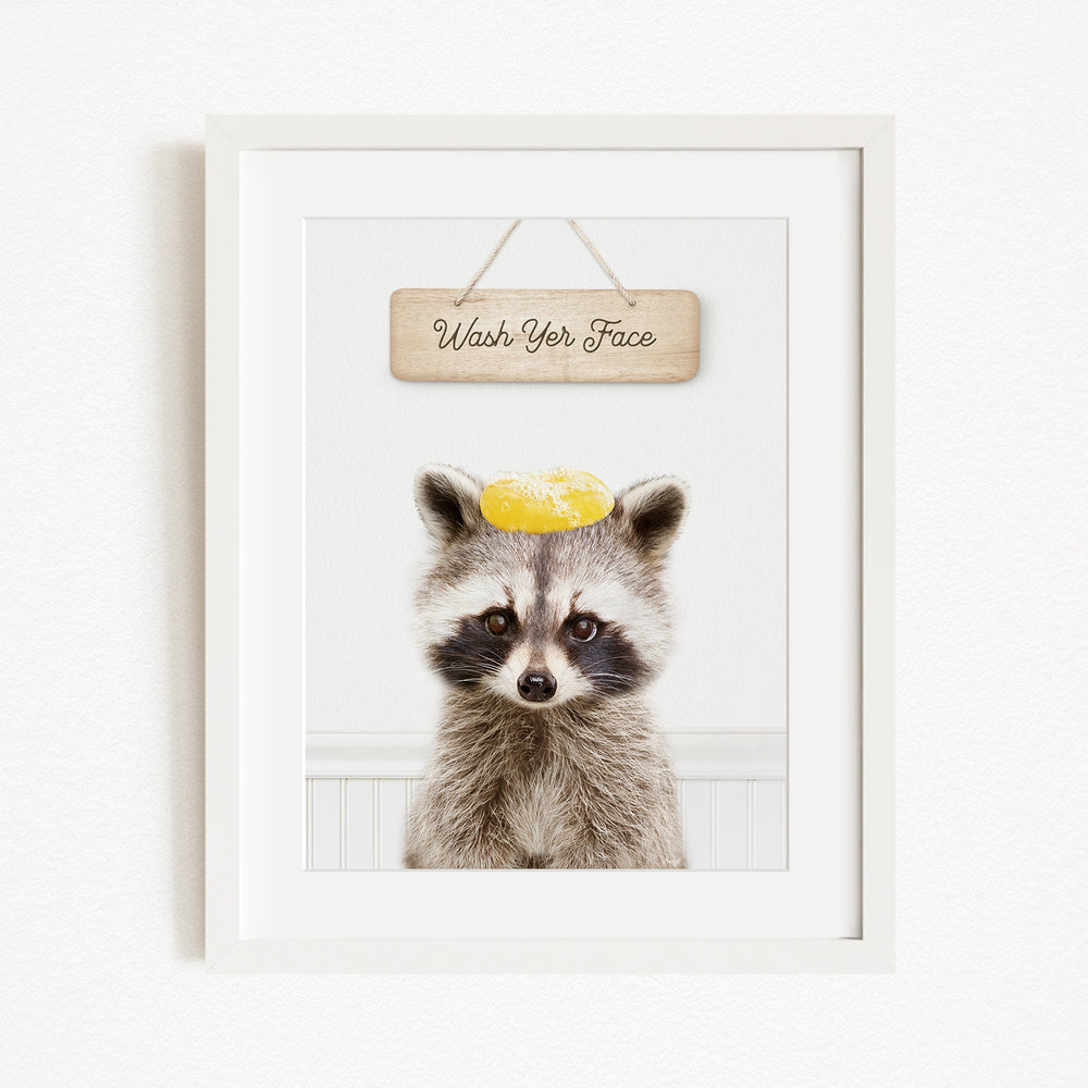 A raccoon wearing a yellow hat with the text "Wash Your Face" written on it, hanging on a wall.