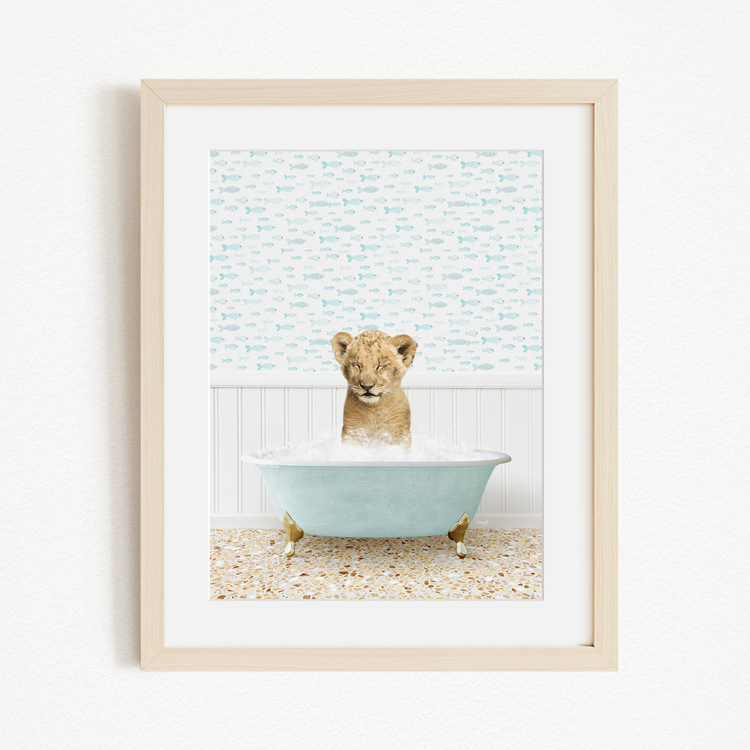 A young lion cub sitting in a blue bathtub filled with water, surrounded by a patterned wall.