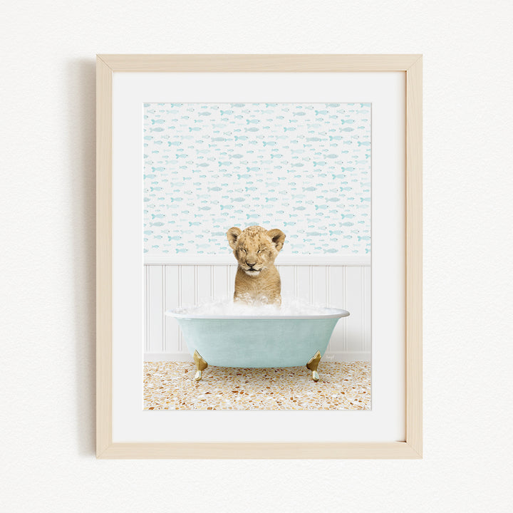 A young lion cub sitting in a blue bathtub filled with water, surrounded by a patterned wall.