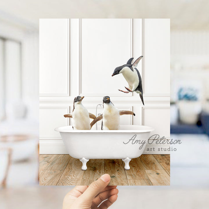 a hand holding a photo of three penguins in a bathtub