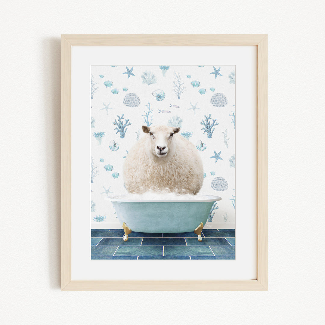 A white sheep is sitting in a blue bathtub, surrounded by a pattern of blue and white seashells and starfish on the wall behind it.