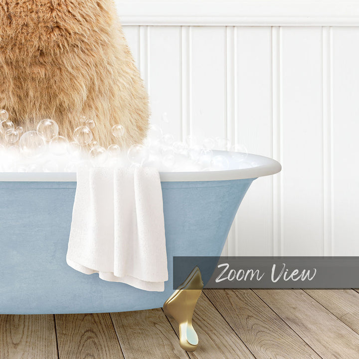 A fluffy brown dog is sitting in a blue bathtub filled with bubbles, with a white towel and gold bathtub leg visible.