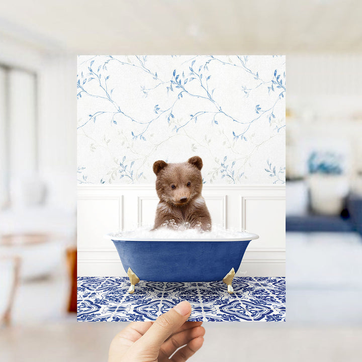 A brown bear sitting in a blue bathtub filled with bubbles, surrounded by a blue and white floral patterned wall.