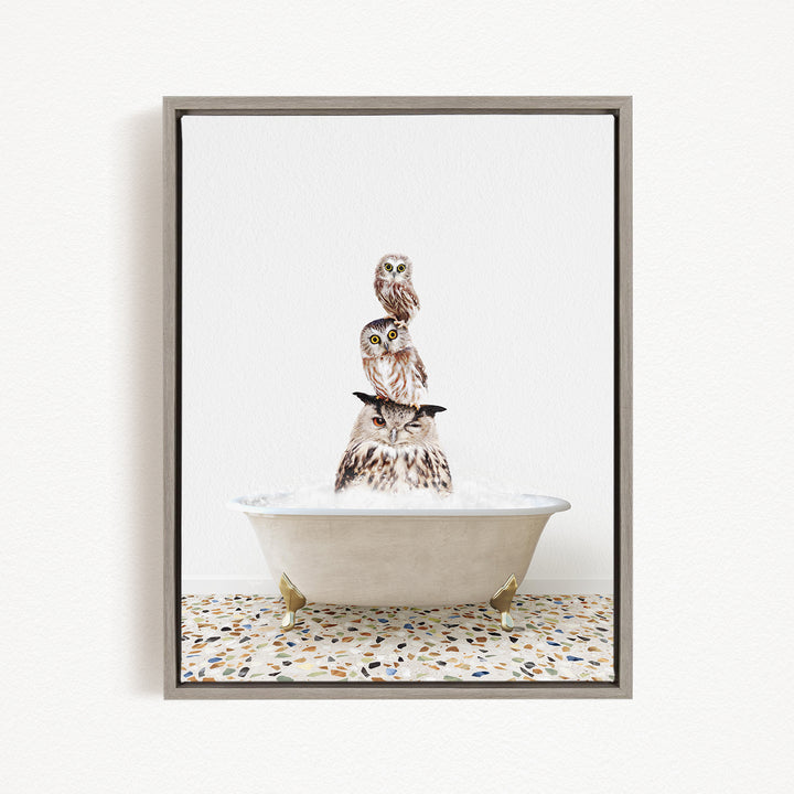 A framed image depicting three owls sitting in a bathtub, with one owl perched on top of the other two.