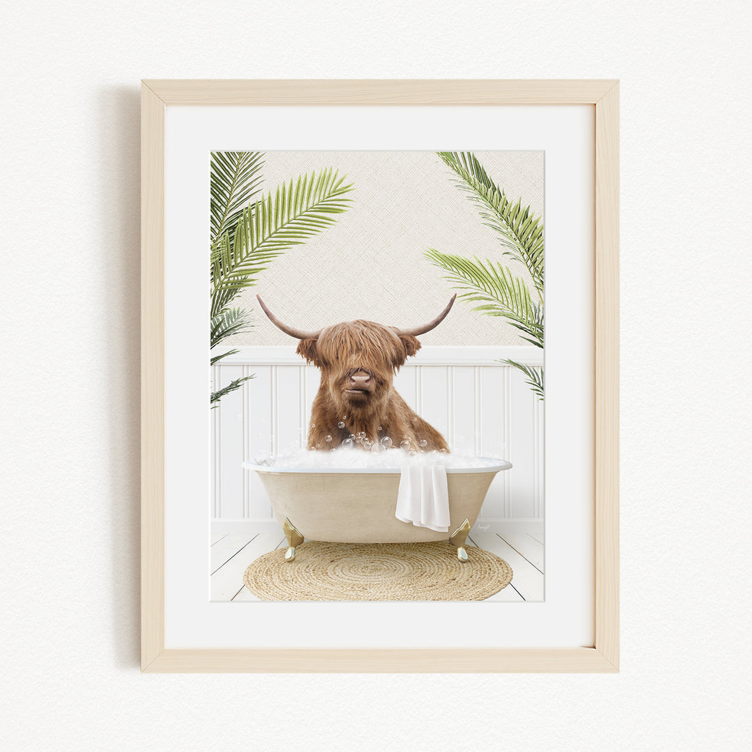 A brown cow with long horns is sitting in a white bathtub filled with water, surrounded by green palm leaves.