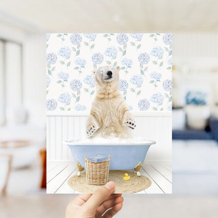 A polar bear sitting in a bathtub filled with bubbles, surrounded by a blue floral patterned wall and a yellow rubber duck.