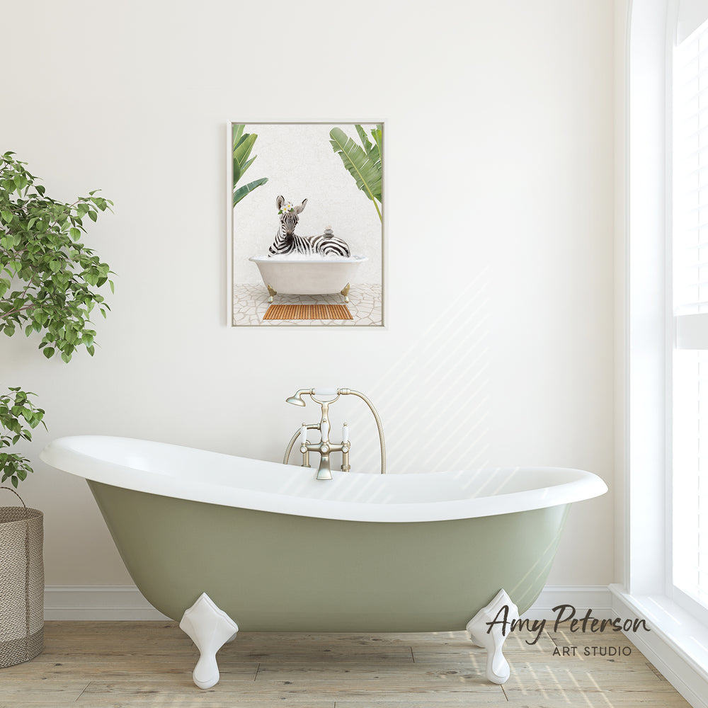 A green clawfoot bathtub with a zebra sitting in it, set against a white wall with a framed picture of a zebra above it.