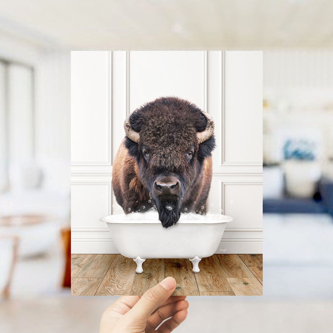 A large, furry bison with horns is sitting in a white bathtub, surrounded by a blurred background.