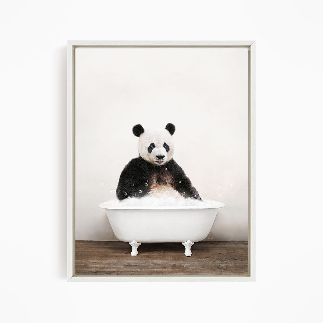 A panda bear sitting in a white bathtub filled with bubbles, looking directly at the camera.