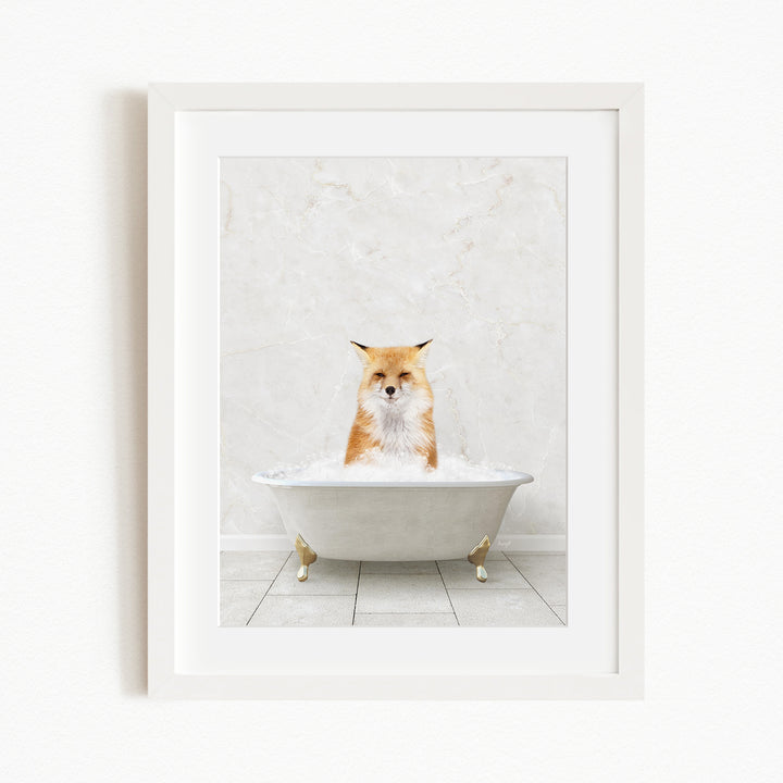 A red fox is sitting in a white bathtub filled with bubbles, looking directly at the camera.