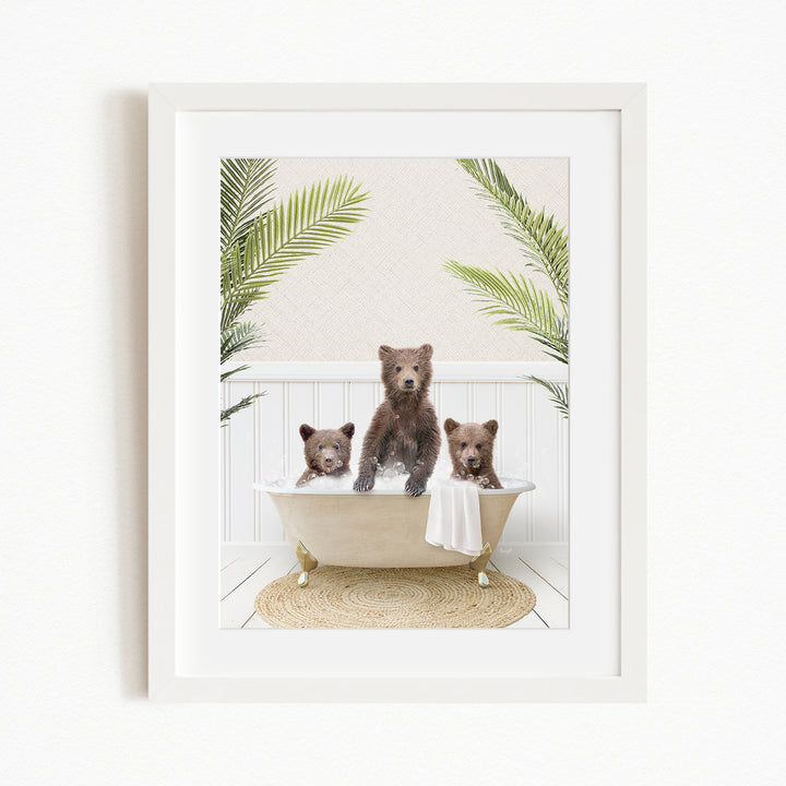 A framed image depicting three brown bears sitting in a bathtub, surrounded by green palm leaves.