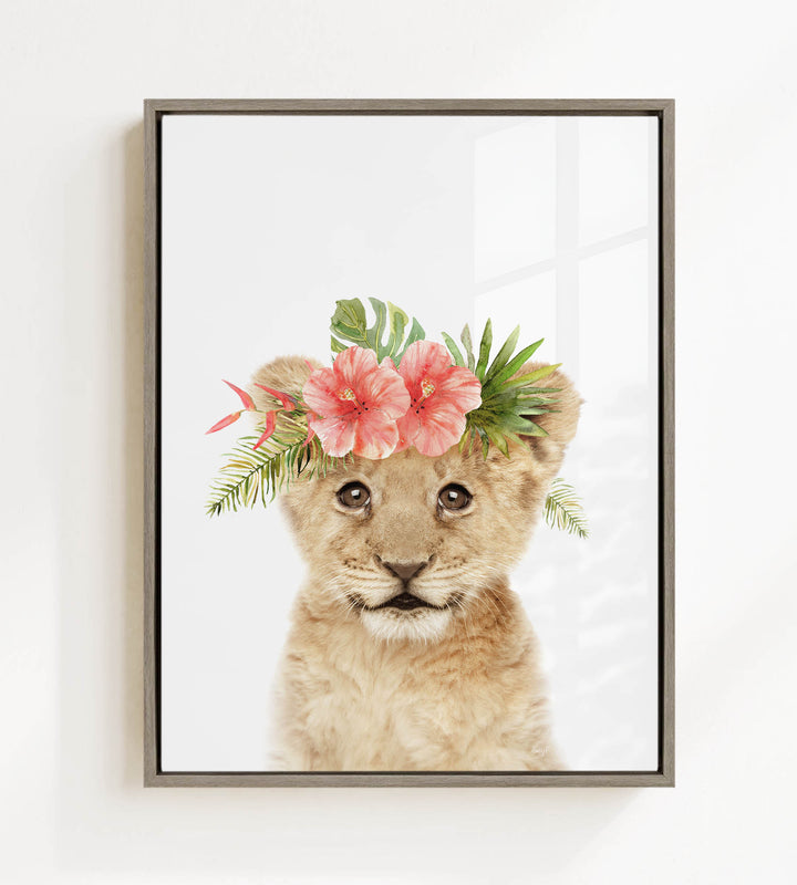 A young lion cub wearing a floral crown on its head, with pink flowers and green leaves adorning its head.