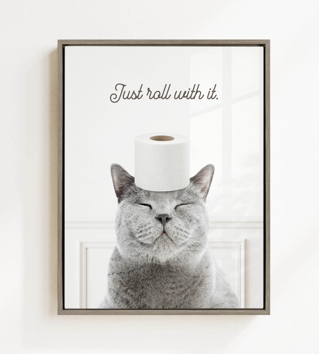 A gray cat with its eyes closed and a roll of toilet paper on its head, with the text "Just roll with it."
