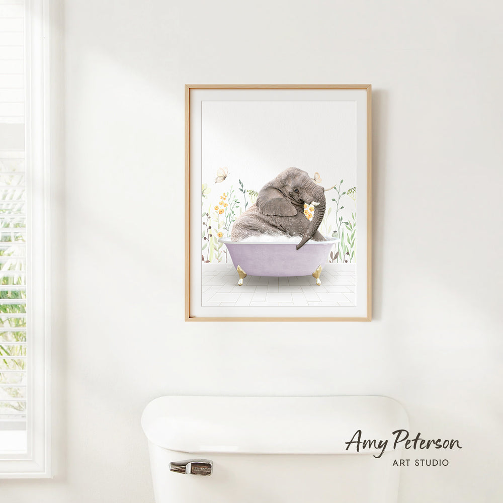 A framed illustration of an elephant sitting in a bathtub, surrounded by flowers, is hanging on a white wall.