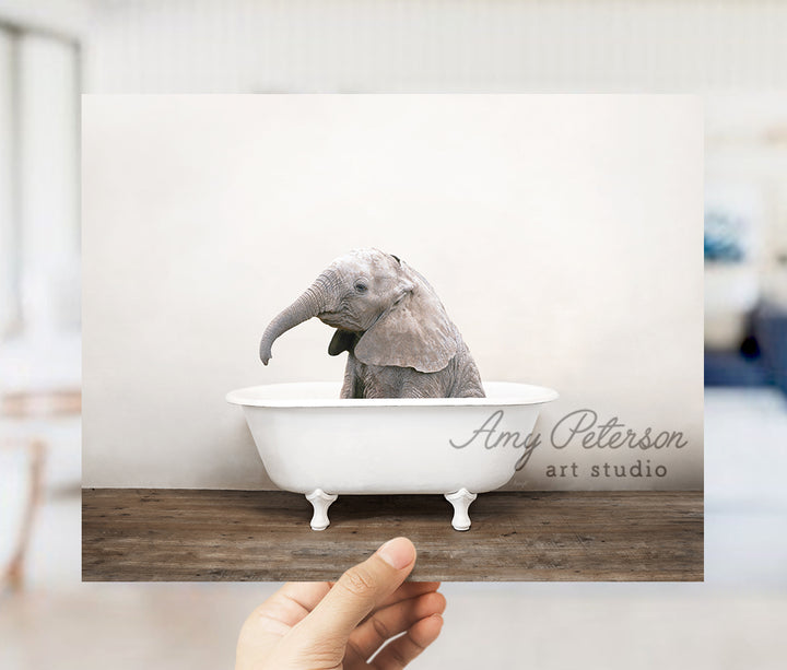 a person holding up a picture of an elephant in a bathtub