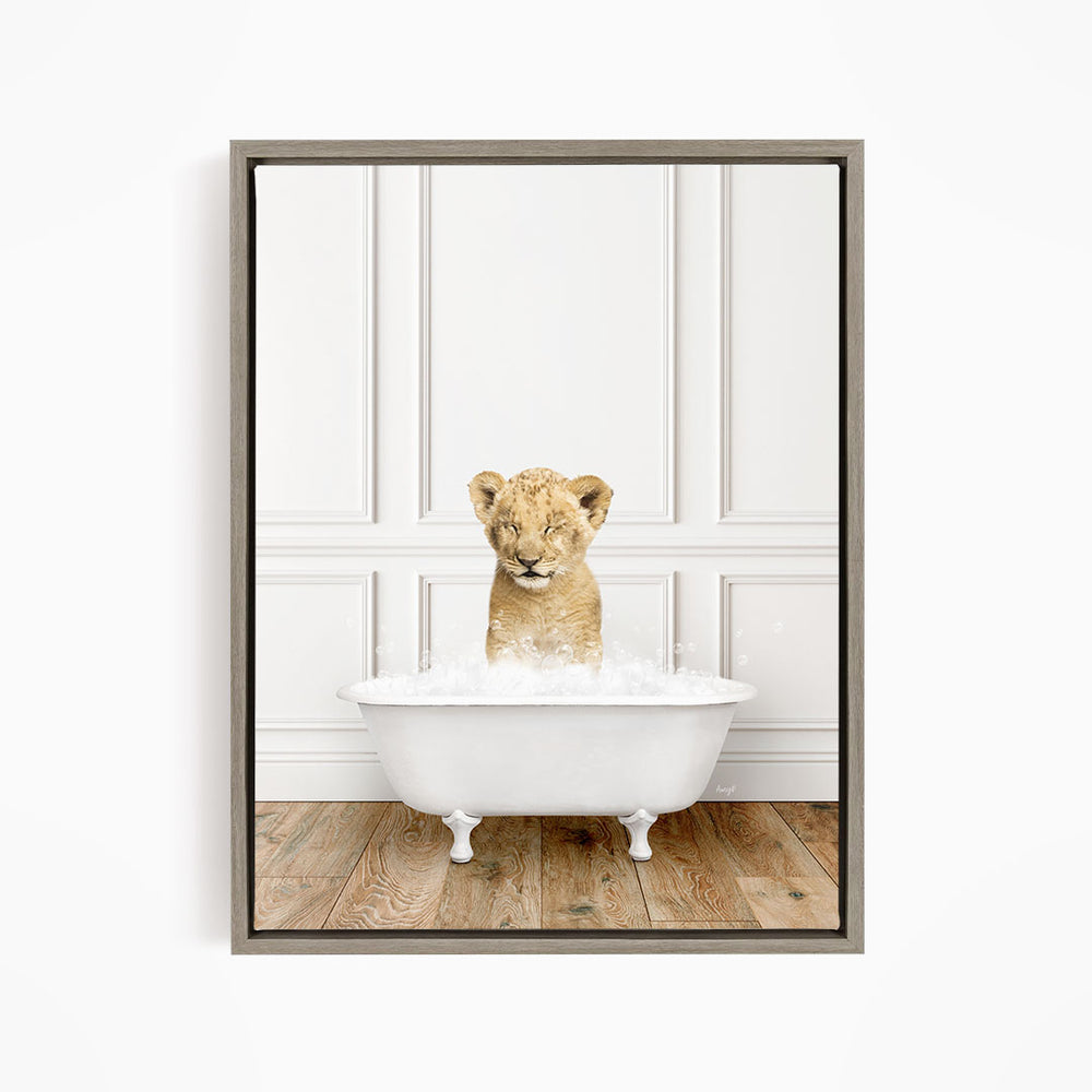 A young lion cub sitting in a white bathtub filled with water, looking at the camera with a playful expression.