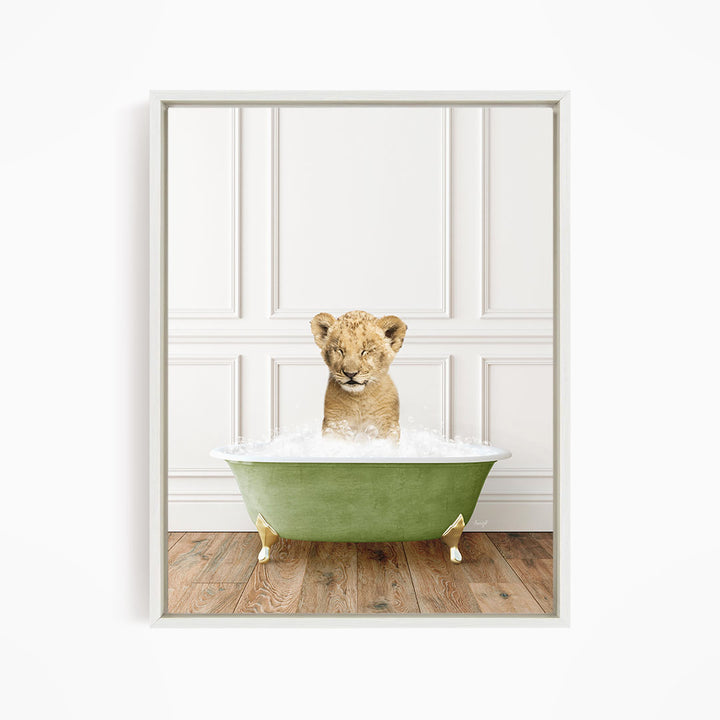 A young lion cub sitting in a green bathtub filled with water, looking at the camera with a playful expression.