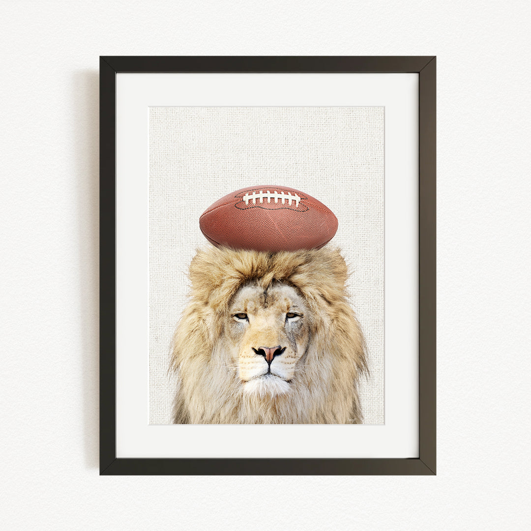 A framed image of a lion with a football on its head.