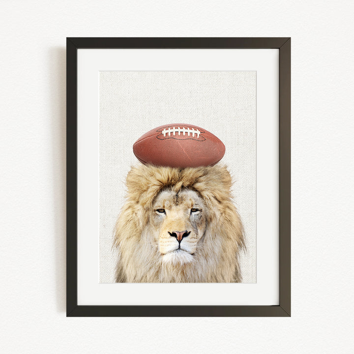 A framed image of a lion with a football on its head.