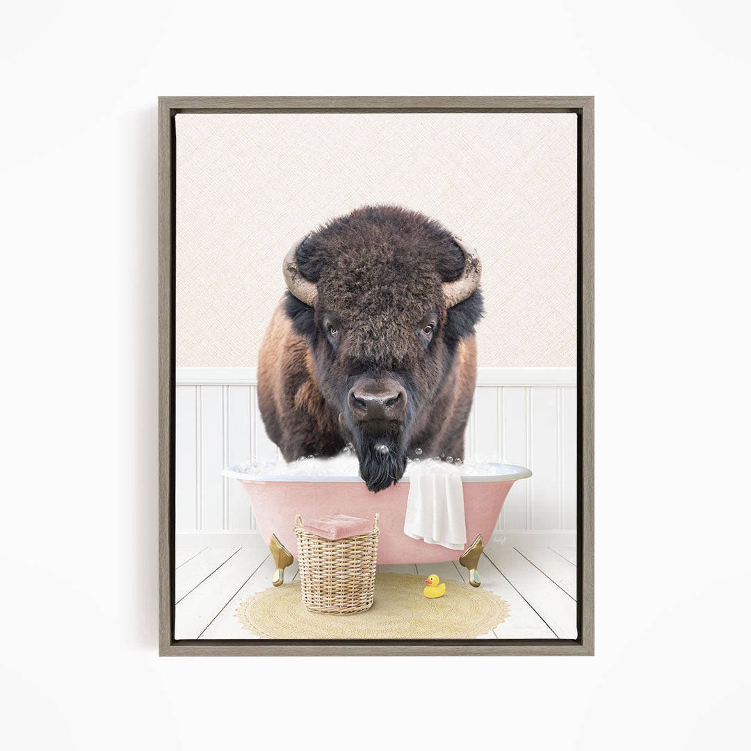 A buffalo standing in a pink bathtub, surrounded by a basket of toys and a towel.