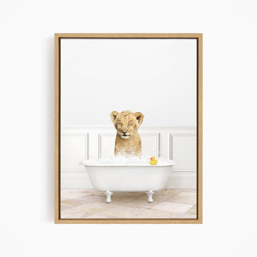 A young lion cub sitting in a white bathtub, surrounded by bubbles and a rubber duck.