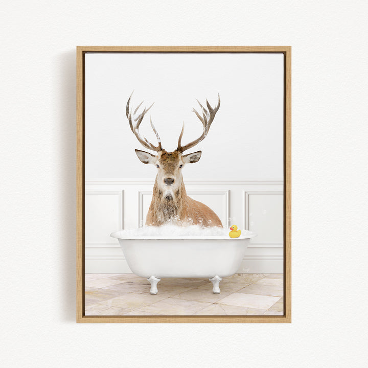 A deer with large antlers is sitting in a white bathtub filled with bubbles, with a yellow rubber duck floating in the water.