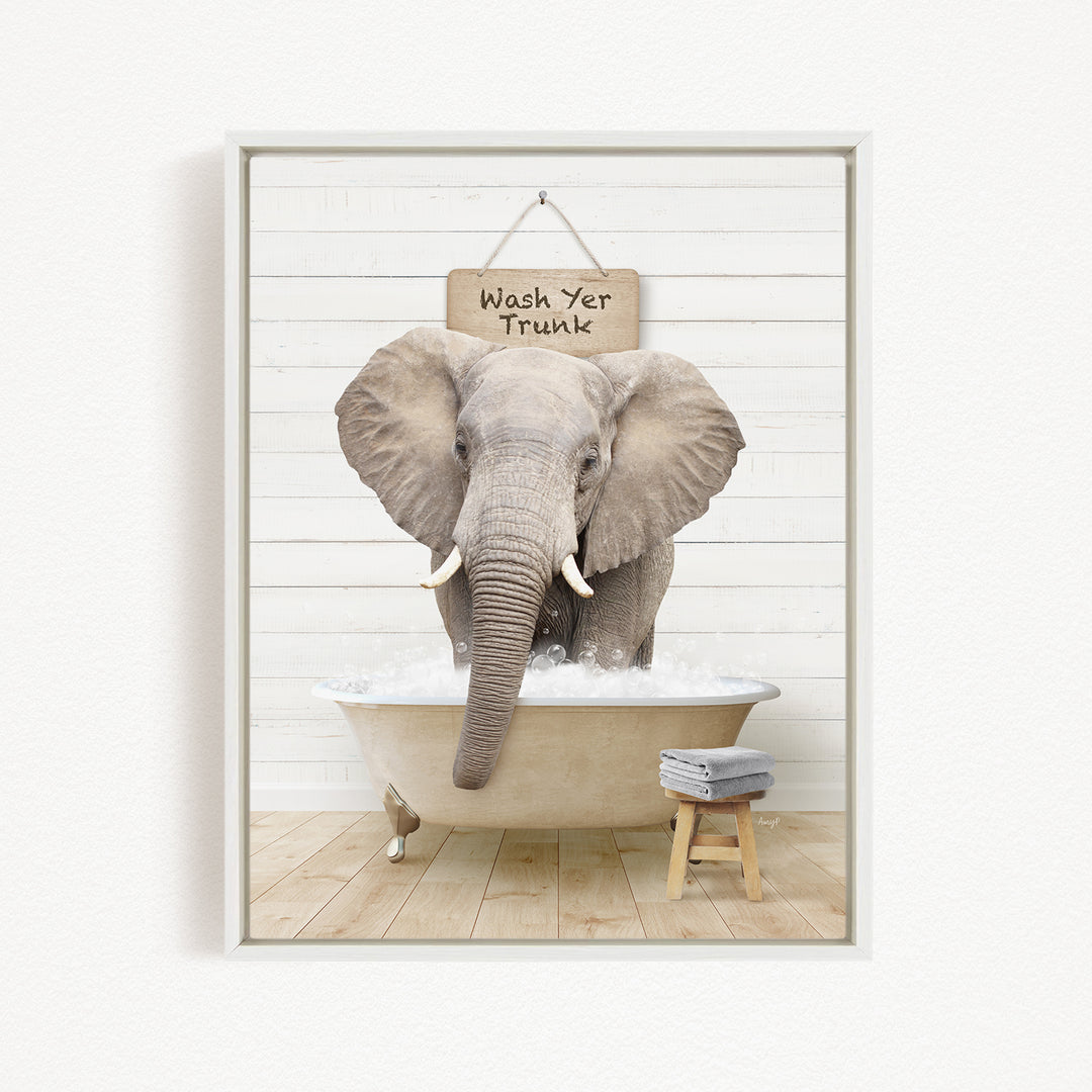 A gray elephant standing in a bathtub filled with water, with a sign above it that says "Wash Yer Trunk".